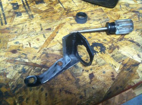 1975 Ford Courier - A metal bracket and a screwdriver are on a wooden workbench.