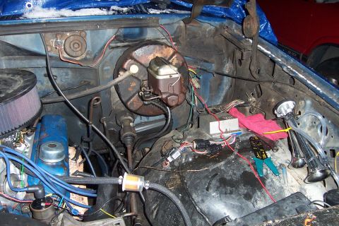 1980 Ford Bronco - Engine bay details including brake booster, air filter, and various electrical components. A red vehicle is visible in the background.