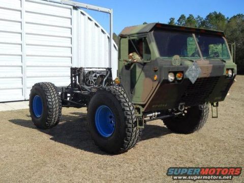 1994 Ford Bronco - This military truck chassis features a camouflage cab and large off-road tires with bright blue rims.