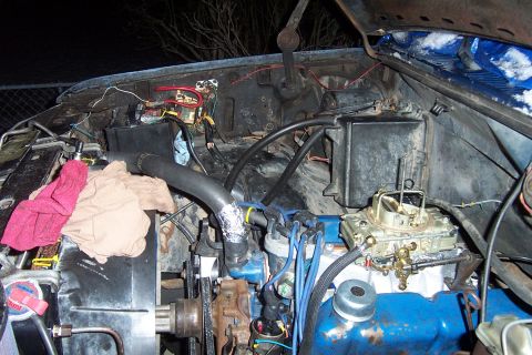 1980 Ford Bronco - The engine bay of a vehicle is shown with a carburetor and various hoses and wires visible.