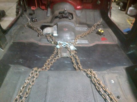 1985 Jeep CJ7 - Chains are secured to the vehicle's frame, suggesting it's being prepared for transport or work.