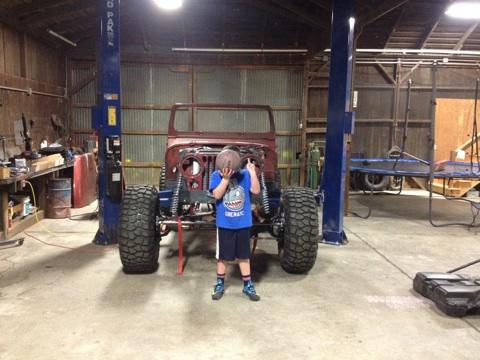 1985 Jeep CJ7 - A 1985 Jeep CJ7 body is being worked on in a garage, with a child obscuring the front.