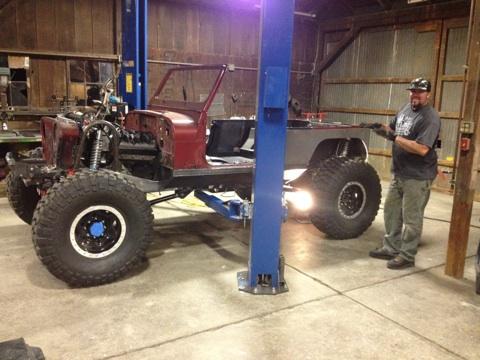 1985 Jeep CJ7 - A man works on a Jeep CJ that is raised on a vehicle lift in a garage.