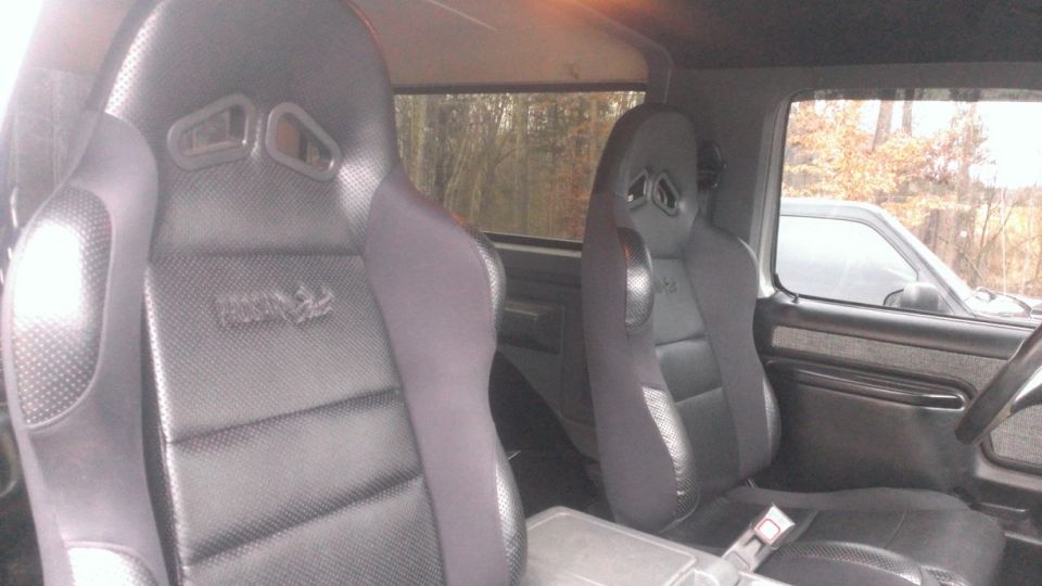 1988 Ford Bronco interior with two black racing seats and a center console
