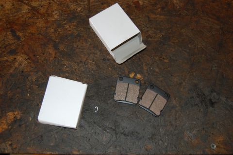 2006 Honda RANCHER - New brake pads are shown next to their packaging on a workbench.
