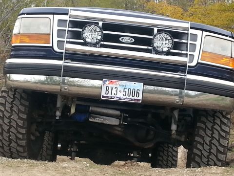1995 Ford Bronco - This lifted Ford truck features a prominent brush guard and auxiliary lighting, with a Texas license plate.