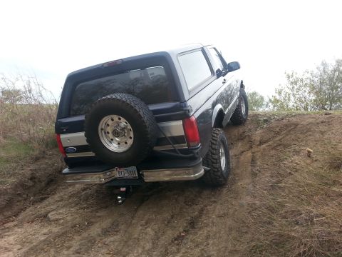 1995 Ford Bronco - This Ford Bronco is navigating a challenging off-road terrain, with its rear facing the camera.