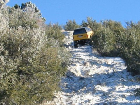 1985 Ford Bronco - Yellow 1985 Ford Bronco navigates a challenging rocky incline on an off-road trail.