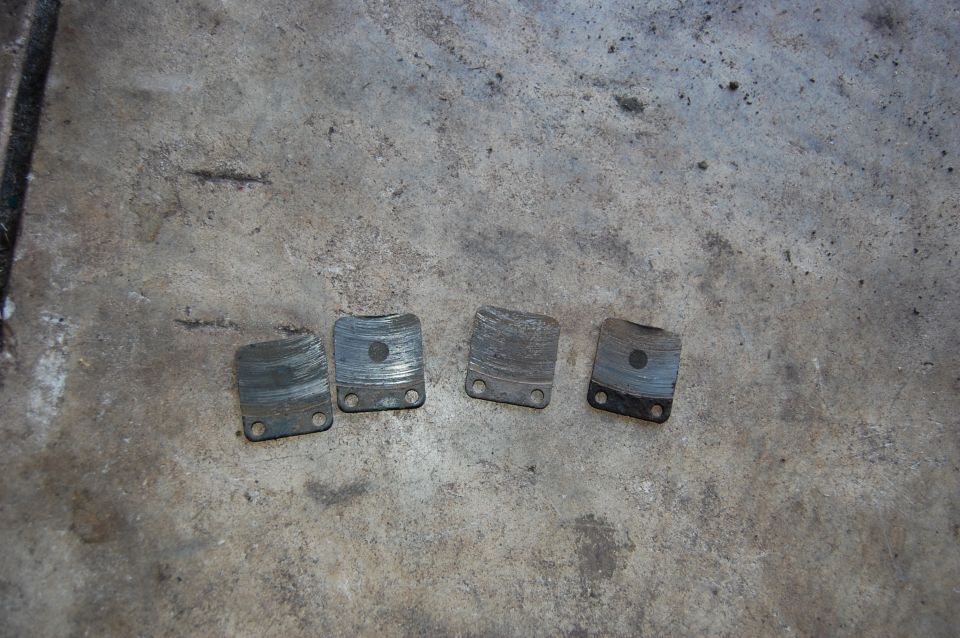 four worn brake pads on concrete