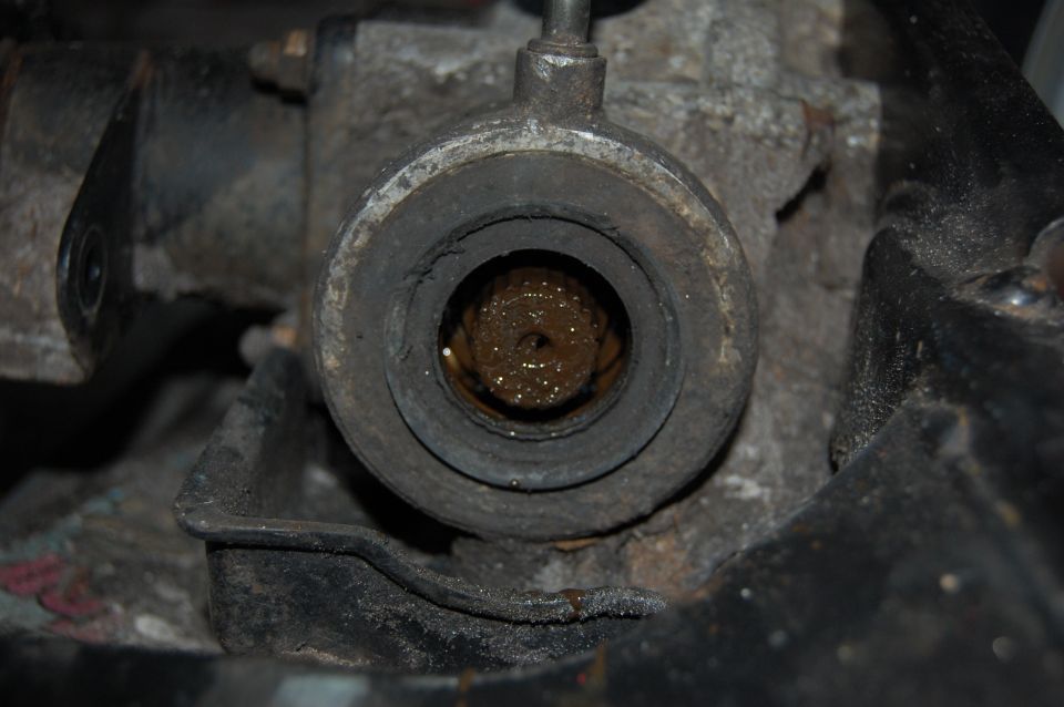 Close-up of a greasy, worn drivetrain part with a splined shaft visible inside