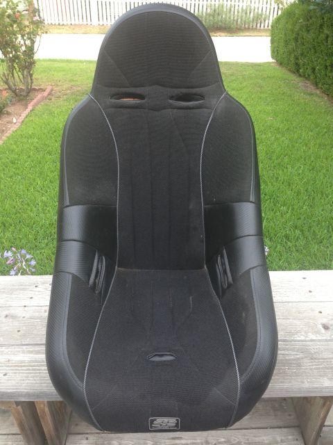 1986 Ford Bronco - A black racing seat with a distinctive design is shown outdoors, placed on a wooden surface.