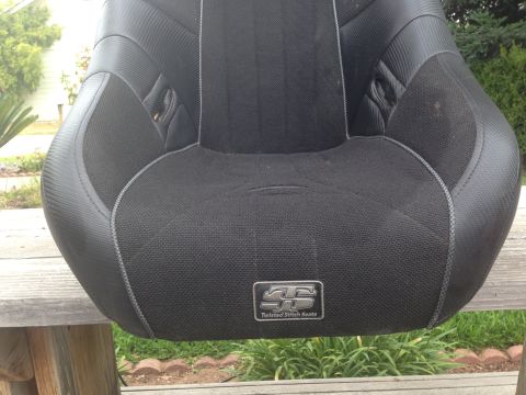 1986 Ford Bronco - A black car seat with a textured fabric and a metallic emblem is shown.