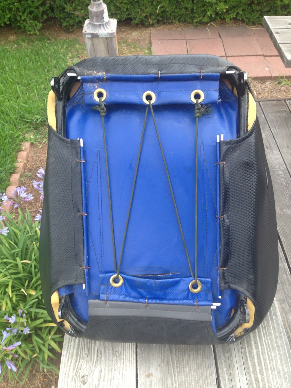 Blue and black car seat upholstery with bungee cords on a wooden surface