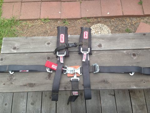 1986 Ford Bronco - A Simpson racing harness is laid out on a wooden surface, showing its straps, buckles, and red tags.