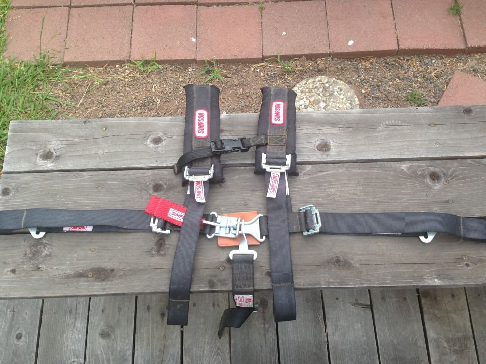 Simpson racing harness with red tag and orange buckle