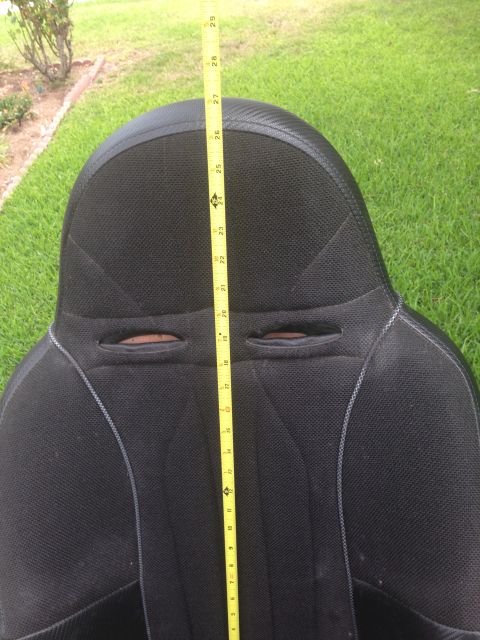 1986 Ford Bronco - A black car seat is measured with a yellow tape measure, showing its dimensions against a grassy background.