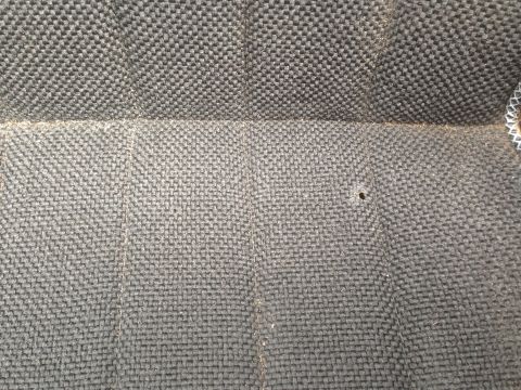 1986 Ford Bronco - Detail of woven seat upholstery, showing texture and a small puncture.
