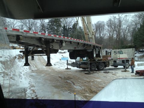 2003 Peterbilt 379 - A flatbed trailer is being loaded onto a truck at a construction site in snowy conditions.