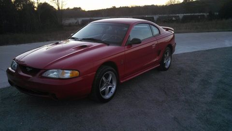 1997 Ford Mustang - A red Ford Mustang coupe is parked outdoors during the day.