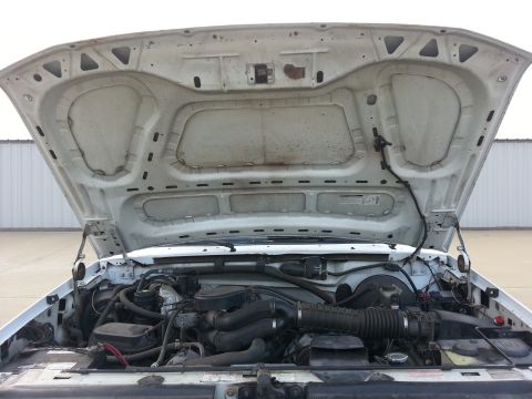 1996 Ford Bronco - The engine bay of a white vehicle is visible with the hood fully open, revealing the engine and associated parts.