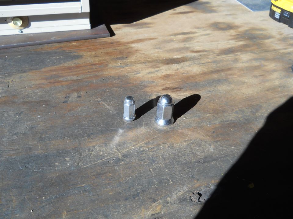 Two lug nuts on a wooden surface