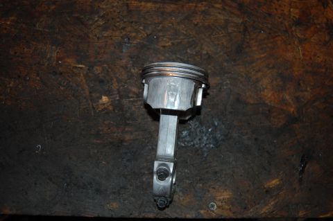 2006 Honda RANCHER - A piston and connecting rod assembly is shown against a dark wooden background.