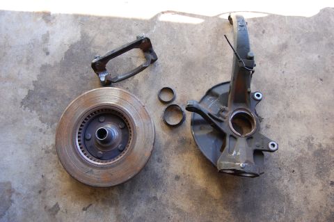 1994 Ford Bronco - Disassembled brake components including rotor, caliper bracket, and spindle.