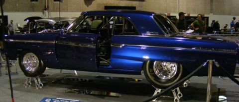 1965 Ford Fairlane - A modified blue coupe is displayed with its doors open, revealing a roll cage inside.