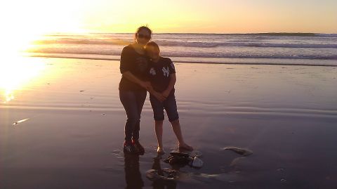 1996 Ford Bronco - Sunset over the ocean with a mother and child standing on the beach.