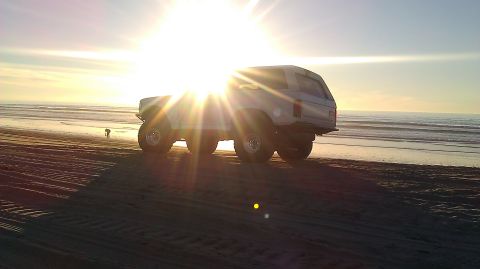 1996 Ford Bronco - White 1996 Ford Bronco parked on a sandy beach during a sunset.
