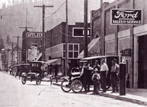 1917 Ford Model T - Street view of a Ford dealership with multiple early automobiles parked outside.