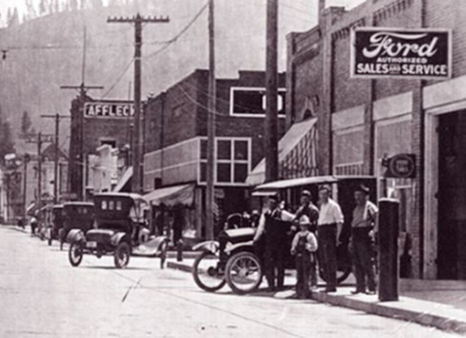 1917 Ford Model T town car parked outside Ford authorized sales and service building with other vehicles on street