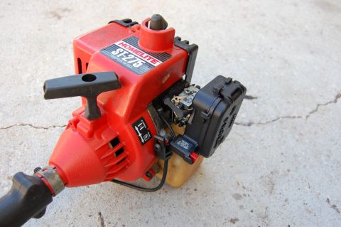2006 Honda RANCHER - Close-up of a Homelite ST-275 string trimmer engine, showing the starter mechanism and carburetor.