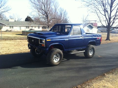1982 Ford Bronco - This lifted blue Ford Bronco has a custom hood scoop and large off-road tires.