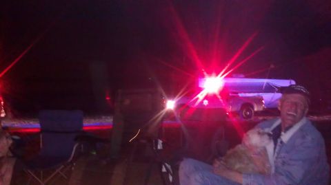 1996 Ford Bronco - A man and his dog are seen at night with a trailer and a dark SUV, illuminated by flashing red lights.