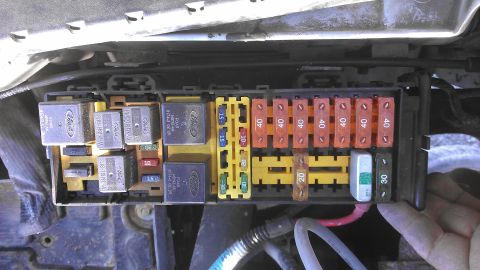 1990 Ford Bronco - Close-up view of a vehicle's electrical fuse box, showing multiple relays and fuses with amperage ratings.