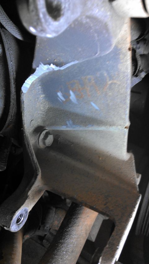 1990 Ford Bronco - Close-up of a damaged engine bracket showing rust and a bolt head.