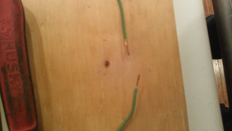 1990 Ford Bronco - Two green wires with exposed copper ends are visible on a wooden surface, next to a red tool.
