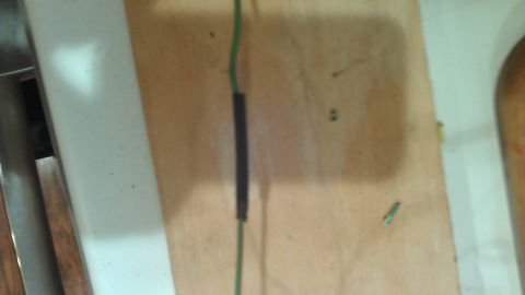 1990 Ford Bronco - A close-up view of an electrical wire with heat shrink tubing, against a wooden background.