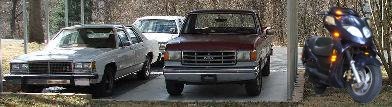 1991 Ford Crown Victoria LTD - Multiple vehicles are parked in a lot, including a sedan, a truck, a van, and a scooter.