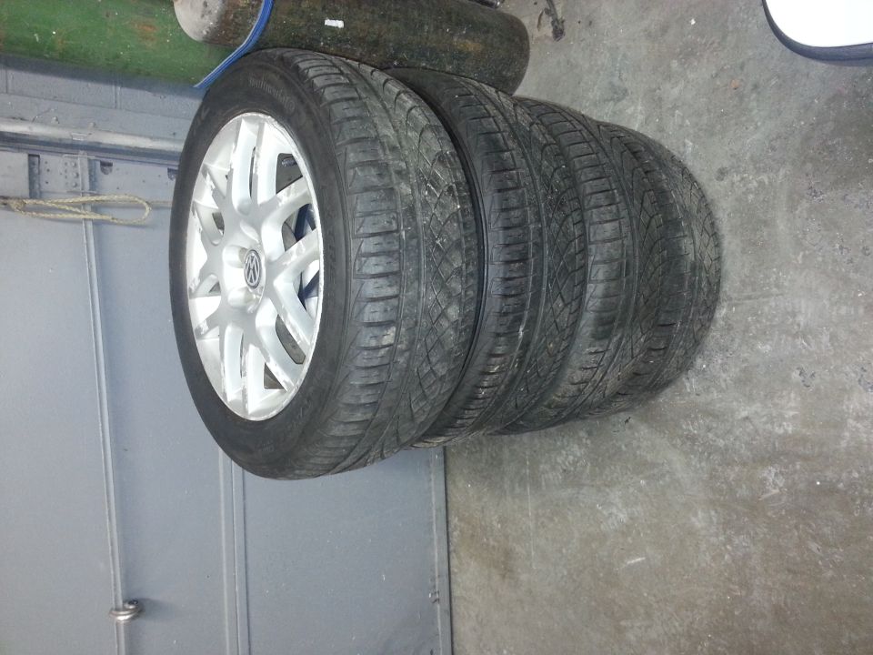 Four stacked tires with silver rims, one rim has a Volkswagen logo
