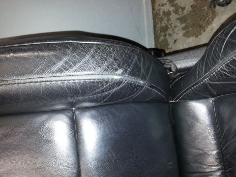 2002 Volkswagen Jetta - Close-up of worn black leather car seats showing signs of age and use, including cracking and a small blemish.
