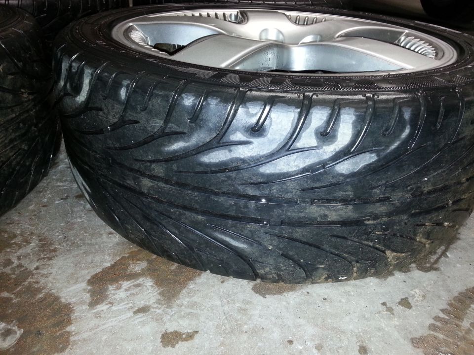 Tire with aggressive tread pattern and silver alloy wheel, close-up