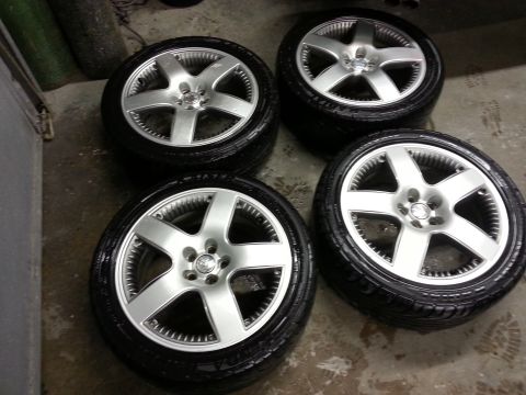 2002 Volkswagen Jetta - Four alloy wheels with tires are displayed, one of which features a Volkswagen logo, suggesting they are parts for a Volkswagen vehicle.