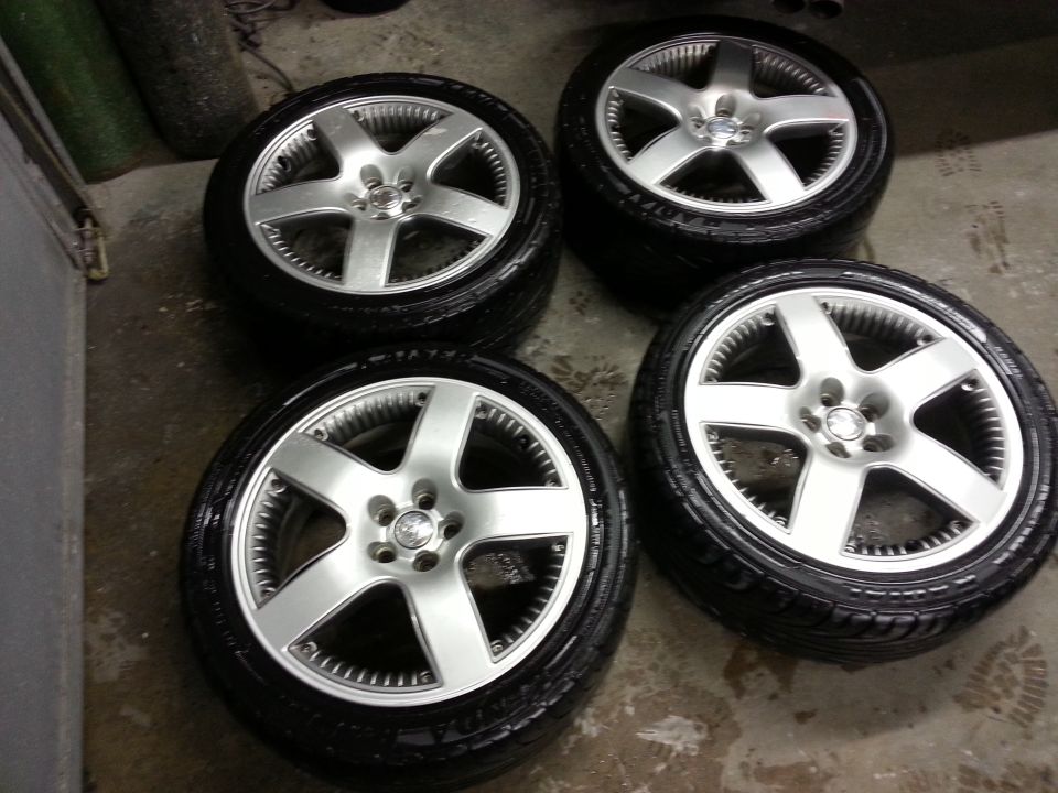 Four silver alloy wheels with tires, one with a Volkswagen logo