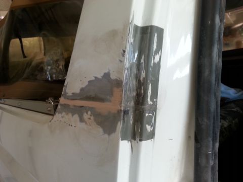 1992 Ford Bronco - Close-up of a vehicle's body panel showing repair work with body filler and tape.