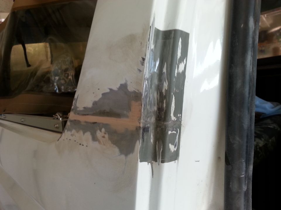 White vehicle body panel with gray body filler and black tape applied to a seam