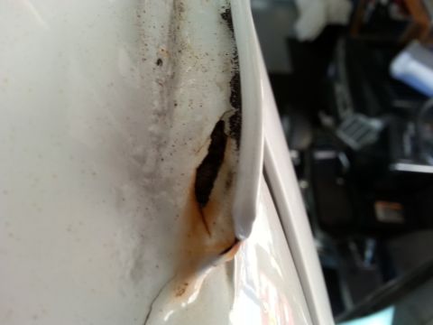 1992 Ford Bronco - Close-up view of rust forming on the edge of a white vehicle's door.