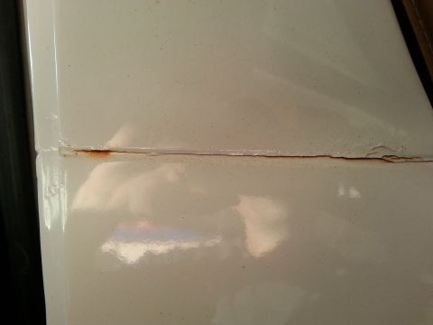1992 Ford Bronco - Rust is visible along the seam of a white vehicle panel, indicating potential body work issues.