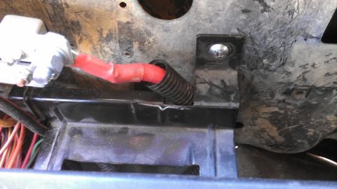 1990 Ford Bronco - A close-up view of a vehicle's wiring harness and mounting bracket, with visible electrical tape and protective tubing.